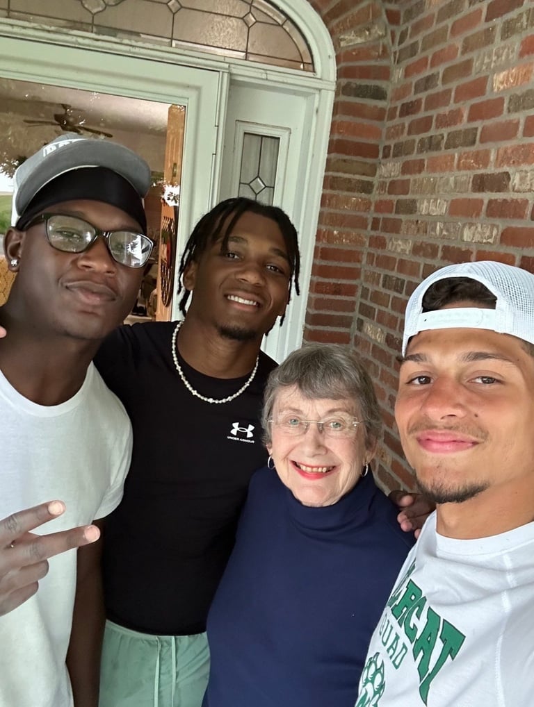 Four people smiling at camera indoors against brick wall and mint green door